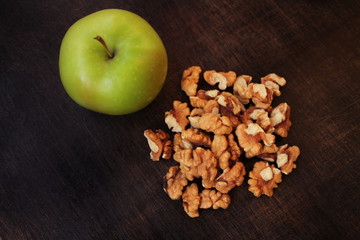 Apple and walnuts on a wooden background
