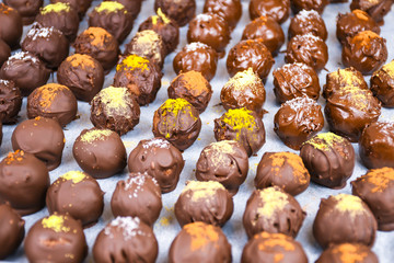Group of sweet and tasty homemade chocolate balls on a backing paper sprinkled with different spice flavors close up