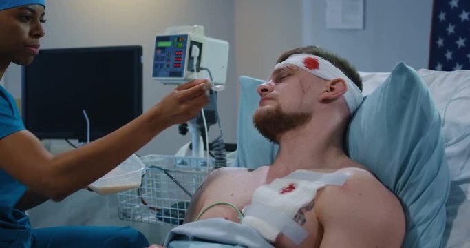 Nurse feeding injured soldier in hospital bed