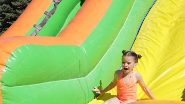 Slow motion shot children sliding down inflatable water slide