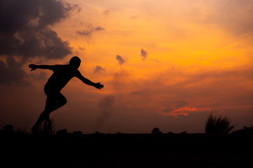 Naklejka na ściany i meble Man running alone at beautiful sunset in the road at park . Summer sport and freedom concept. Athlete training on dusk. - Image