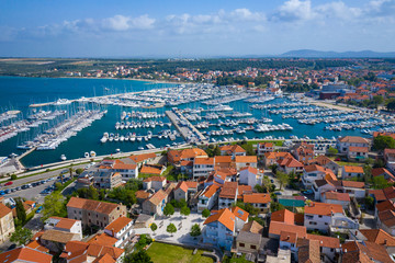 Aerial View of Yacht Club and Marina in Biograd na Moru. Summer time in Dalmatia region of Croatia. Coastline and turquoise water and blue sky. Photo made by drone from above.