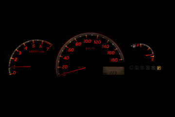 The dashboard of the car is glowing white with orange arrows at night with a speedometer, tachometer and other tools to monitor the condition of the vehicle in classic style