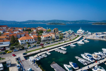 Naklejka na ściany i meble Aerial View of Yacht Club and Marina in Biograd na Moru. Summer time in Dalmatia region of Croatia. Coastline and turquoise water and blue sky. Photo made by drone from above.