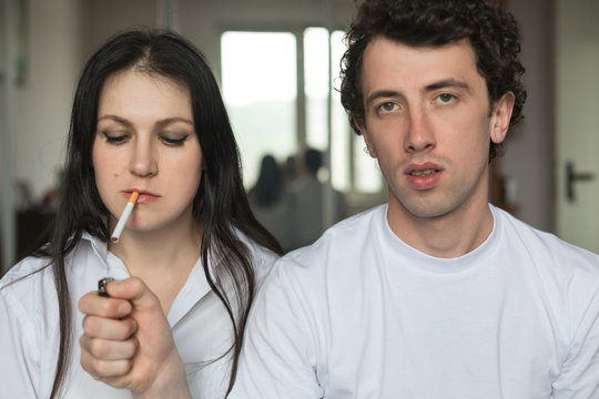 Young man light in a cigarette to a young woman.