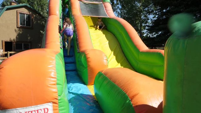 Slow motion shot of boy sliding down inflatable water slide