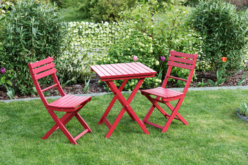 Relaxing area with two red chairs and red table in cozy garden