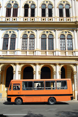 Fototapeta na wymiar La Havane, immeuble à arcades le long du Paséo del Prado, bus orange stationné, Cuba, Caraïbes