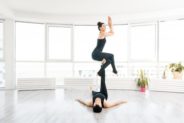 Young couple doing acro yoga in pair at studio