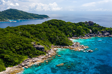 Fototapeta na wymiar Aerial drone view of boats around the shallow coral reef surrounding beautiful tropical islands (Similan Islands)