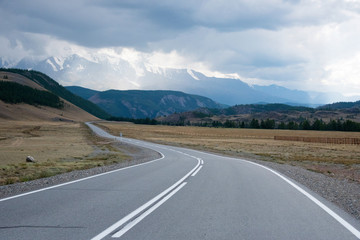 Asphalt winding road in the mountainous area Altai in the summer and sky with clouds