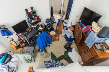 Very messy, cluttered suburban teenage boys bedroom with piles of clothes, music and sports...