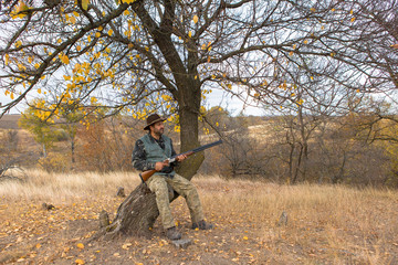 Hunter with a hat and a gun in search of prey in the steppe	