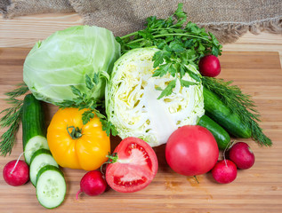 Various fresh vegetables and herbs on a wooden cutting board