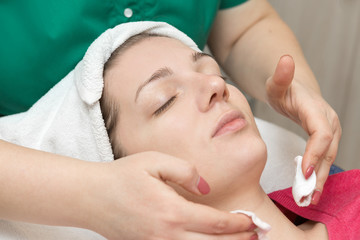 Fototapeta na wymiar Face skin care. Beautician applying beauty oil mask on face using brush In spa salon 