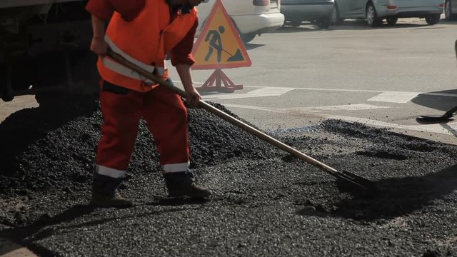 Workers on the road repair asphalt