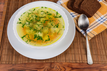 Chicken meatballs soup in the white dish, spoon, bread