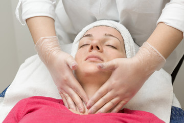 Fototapeta na wymiar Face skin care. Beautician applying beauty oil mask on face using brush In spa salon 