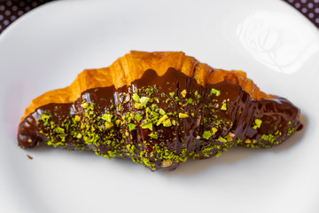 croissant with chocolate and pistachio on a white plate