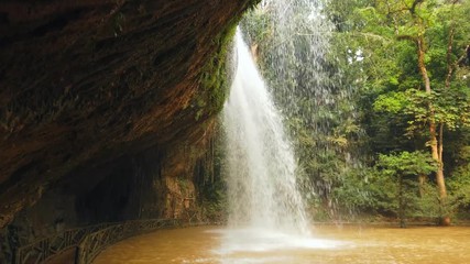 Prenn waterfall full flowing behind fast flow rock falls covered moss close cave depth. Exotic tropics landscape green rainforest trees. Vietnam Dalat park landmark. Travel tourism. Sunny. Gimbal 4k - Powered by Adobe