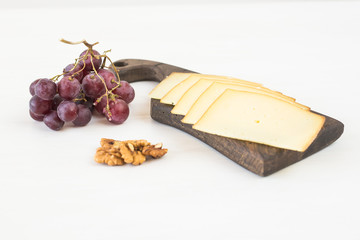 Fresh products. Sliced cheese with grapes and nuts on rustic table.