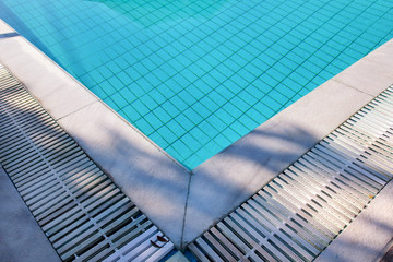Blue ripped water in swimming pool in tropical resort with edge of pavement. Part of Swimming pool bottom background. Clear light blue pool water ripples with sun reflection. Surface of swimming pool.