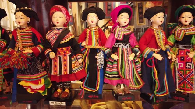 Dolly close details uthentic wooden porcelain dolls in colorful historical costumes traditional Asia Vietnam. Handmade piece of art souvenirs gifts bazaar market.