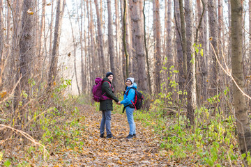Fototapeta premium Travel, tourism, hike and nature concept - Tourists walking in park with backpack dressed in blue and black jackets