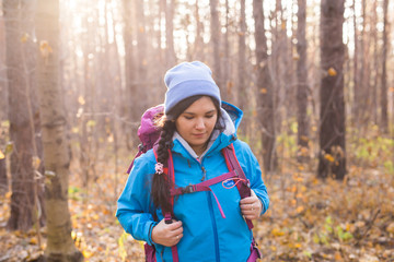 adventure, travel, tourism, hike and people concept - smiling tourist woman walking with backpacks over autumn natural background