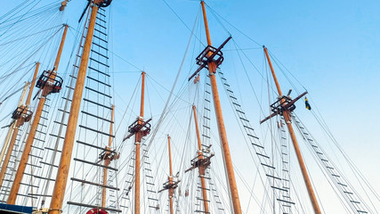 High wooden masts and historical ship rigging against blue sky