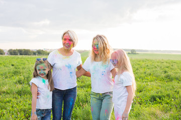 Friendship, Indian holidays and people concept - young women and children having fun on the summer field on festival of holi