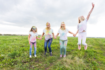 Fototapeta premium Festival of Holi, friendship and holidays concept - young female people on the color dancing and having fun