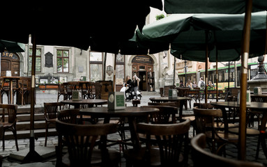 Young and beautiful girls in sunglasses riding a scooter. Portrait of pretty ladies riding a motorbike on old downtown street. Summer vacation. Girls in a black t-shirts on a vintage scooter