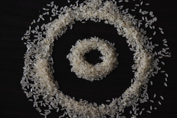 some amount of raw rice laying o the table ,creating a design.background is dark wooden table 