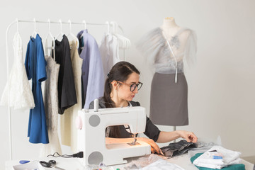 Dressmaker, fashion, tailor and people concept - young female fashion designer working in her...