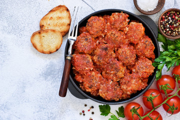 Meatballs with tomato sauce and spices in a pan on the kitchen table. Top view.