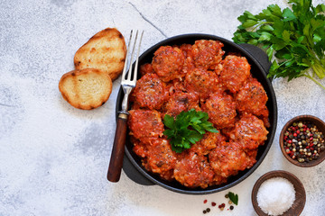Meatballs with tomato sauce and spices in a pan on the kitchen table. Top view.
