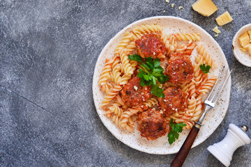 Italian pasta with meat balls, tomato sauce and parmesan on a concrete background.