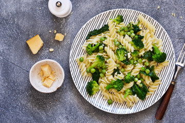 Italian pasta with spinach, broccoli and green peas on a concrete background. Dinner time. Top view.