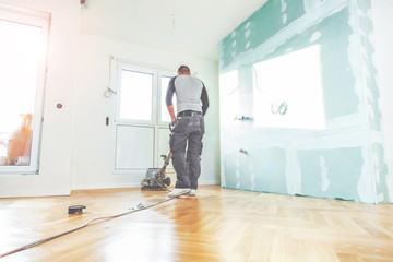 Einölen von Eichenparkett, Arbeiter mit poliermaschine und Werkzeug.