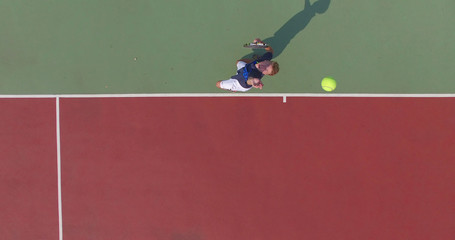 Tennis player throws ball into the air to serve. Overhead view  from drone