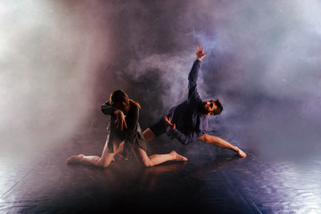 Modern dance couple twisting their legs and lening close to the ground, touching and combining their bodies in extremely unique modern dance experience.