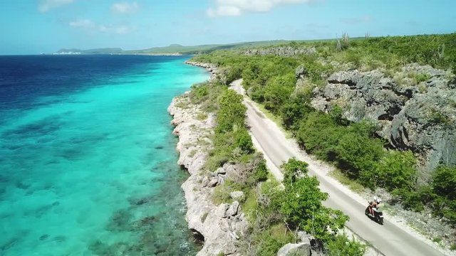 Aerial view of 2 guys riding scooter along coast - Drone shot of coast