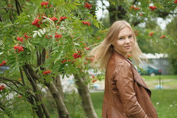 Beautiful blond girl posing for photo in park with wildberry