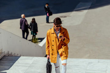 Stylish man with briefcase walking on urban place