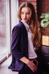 Beautiful fashionable woman in elegant suit near window