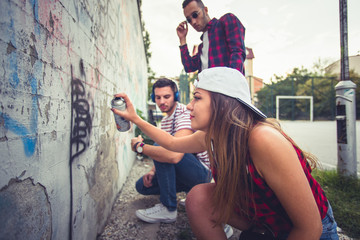 Three friends writing graffiti on the wall