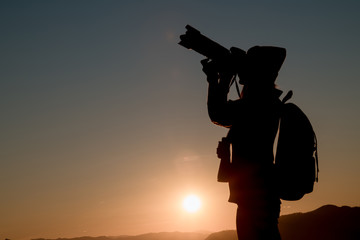 The photographer's silhouette with his camera on a sunset