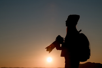 The photographer's silhouette with his camera on a sunset