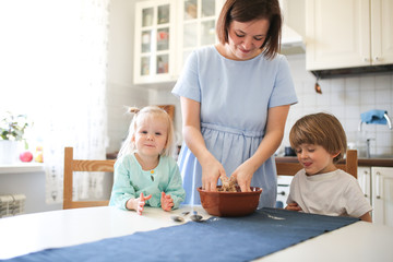 Caucasian brother and sister help mom to cook